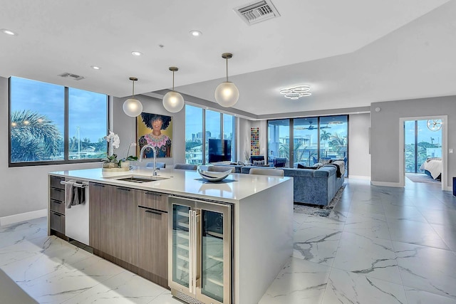 kitchen with dishwasher, sink, hanging light fixtures, beverage cooler, and a center island with sink