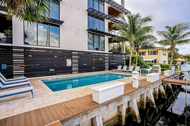 view of pool with a patio, a water view, and area for grilling