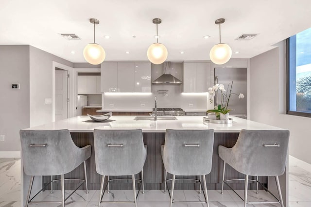 kitchen featuring a spacious island, hanging light fixtures, wall chimney exhaust hood, and a breakfast bar area