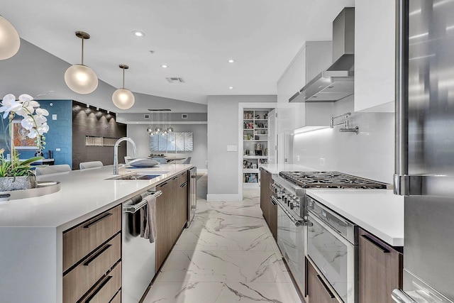 kitchen with appliances with stainless steel finishes, sink, wall chimney range hood, pendant lighting, and a large island