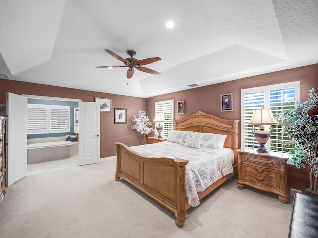 bedroom with a raised ceiling, multiple windows, ceiling fan, and light colored carpet