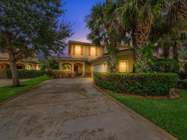 mediterranean / spanish-style home featuring a garage and a lawn