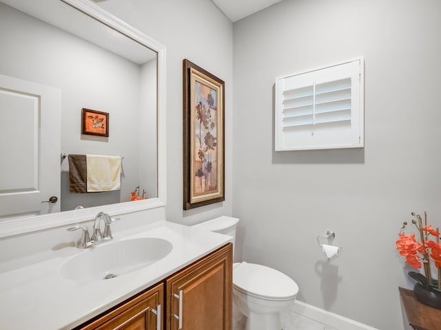 bathroom with toilet, vanity, and tile patterned floors