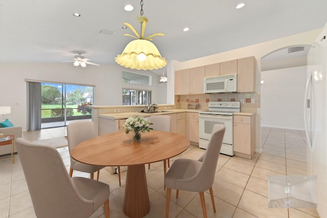 dining area featuring lofted ceiling, sink, and light tile patterned floors