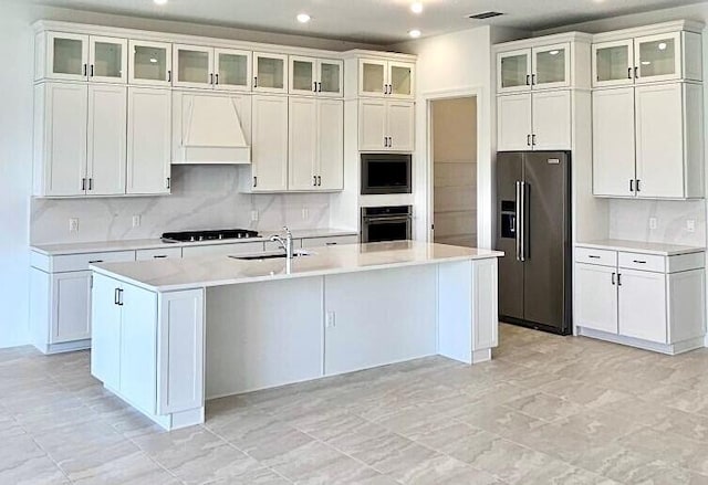 kitchen featuring white cabinets, custom exhaust hood, stainless steel appliances, and a kitchen island with sink