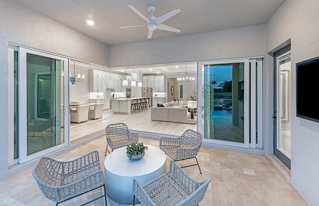 sunroom featuring ceiling fan with notable chandelier