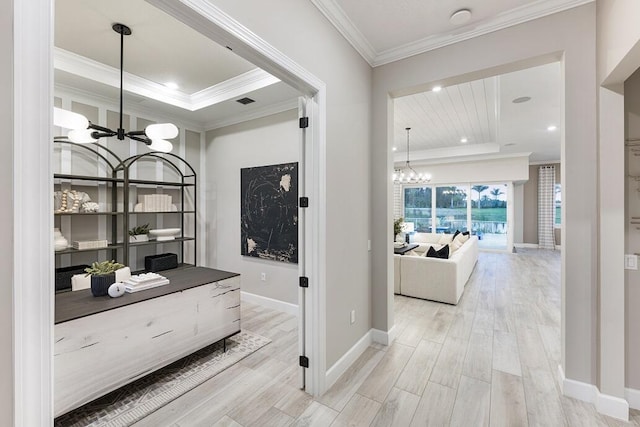 bar featuring hanging light fixtures, an inviting chandelier, a raised ceiling, light hardwood / wood-style flooring, and crown molding