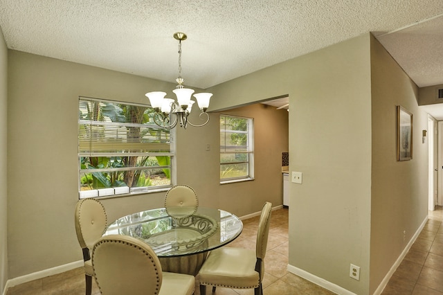 tiled dining area featuring an inviting chandelier and a textured ceiling