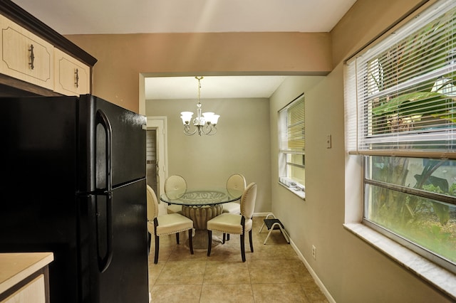 kitchen with black refrigerator, decorative light fixtures, a notable chandelier, white cabinets, and light tile patterned floors