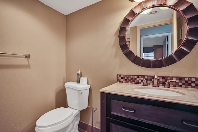 bathroom with vanity, toilet, and tasteful backsplash