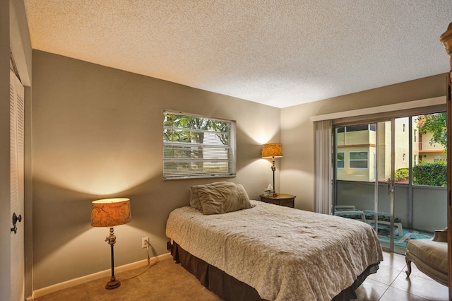 bedroom featuring access to outside, light tile patterned floors, and a textured ceiling