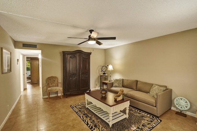 living room with ceiling fan, tile patterned flooring, and a textured ceiling