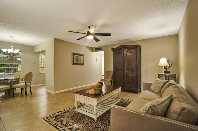 tiled living room featuring ceiling fan with notable chandelier and a textured ceiling