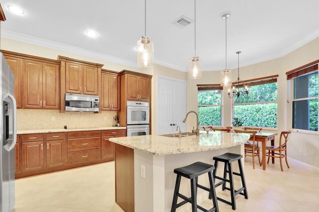 kitchen featuring stainless steel appliances, pendant lighting, crown molding, a chandelier, and a kitchen island with sink