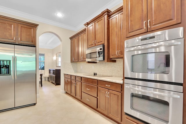 kitchen featuring crown molding, backsplash, stainless steel appliances, light stone counters, and light tile patterned floors