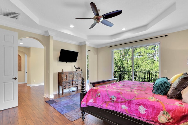 bedroom with ceiling fan, hardwood / wood-style flooring, a tray ceiling, and crown molding