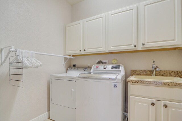 clothes washing area with independent washer and dryer, cabinets, and sink