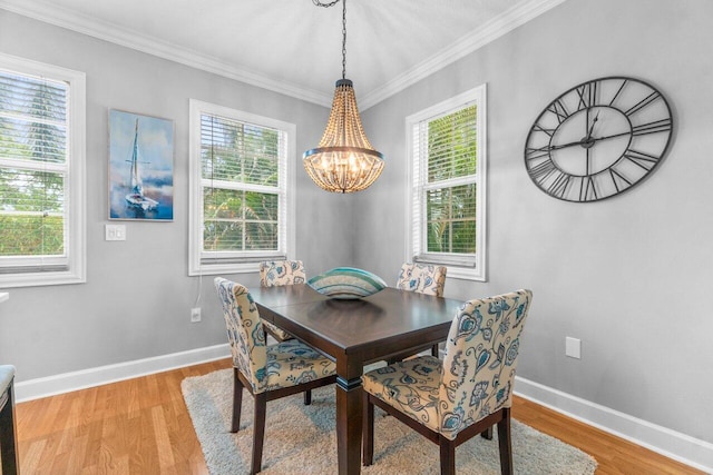 dining space featuring ornamental molding, a notable chandelier, and light hardwood / wood-style flooring