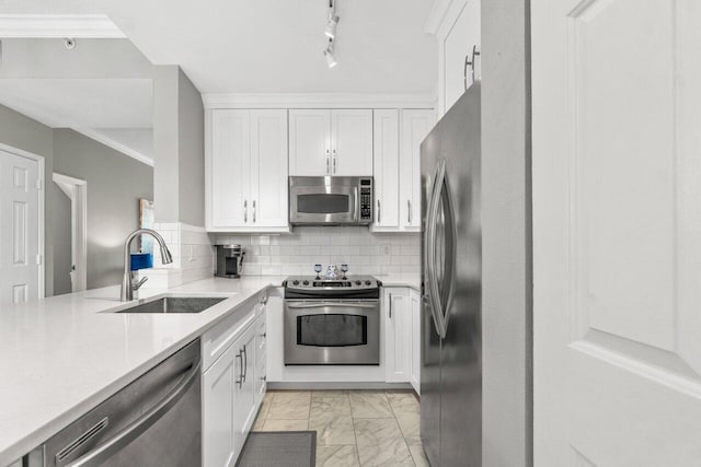 kitchen with sink, white cabinets, track lighting, decorative backsplash, and appliances with stainless steel finishes