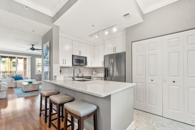 kitchen featuring kitchen peninsula, a breakfast bar area, appliances with stainless steel finishes, white cabinetry, and sink