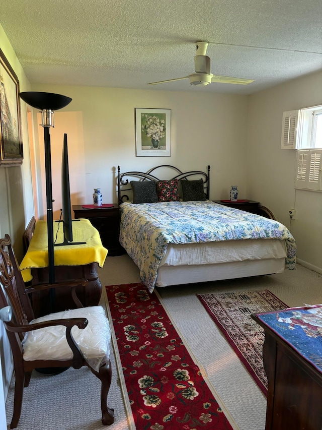 carpeted bedroom featuring ceiling fan and a textured ceiling