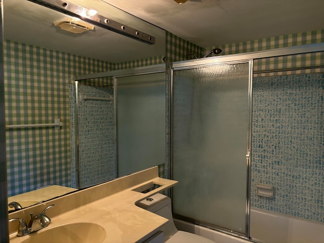 full bathroom featuring toilet, vanity, and shower / bath combination with glass door