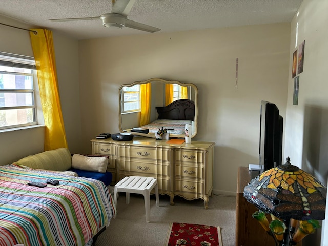 carpeted bedroom with ceiling fan and a textured ceiling