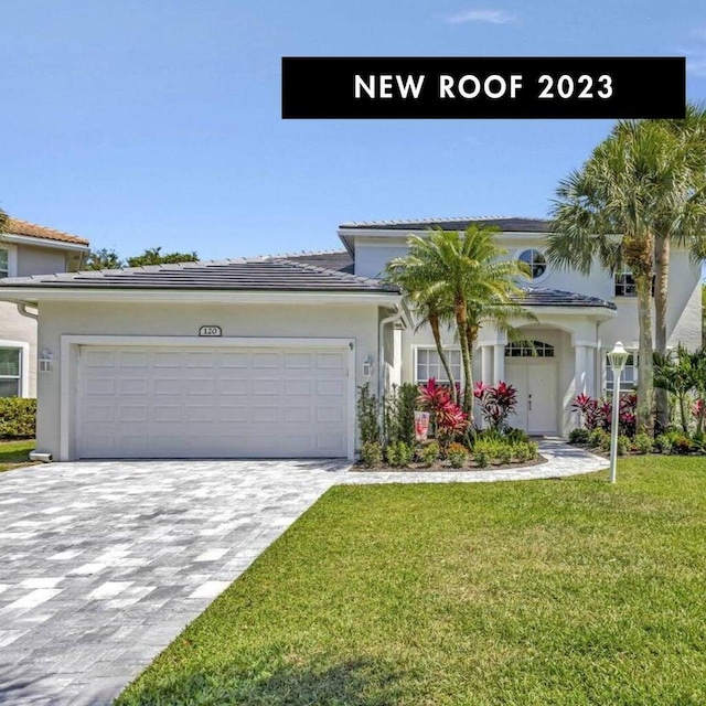 120 Jones Creek Dr, Jupiter, FL 33458 - view of front facade featuring an attached garage, stucco siding, a front yard, decorative driveway, and a tiled roof