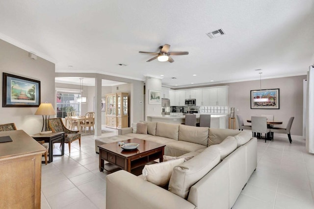 living room with ceiling fan, crown molding, and light tile patterned floors