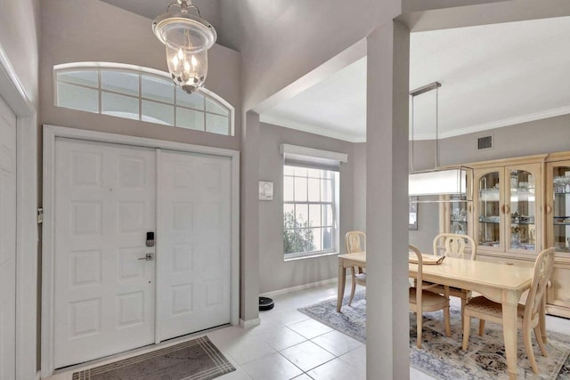 tiled entryway featuring ornamental molding and a notable chandelier