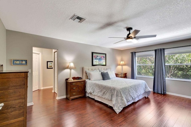 bedroom with dark wood-type flooring, a textured ceiling, and ceiling fan