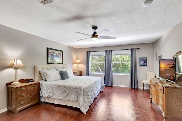 bedroom featuring dark wood-type flooring, a textured ceiling, and ceiling fan