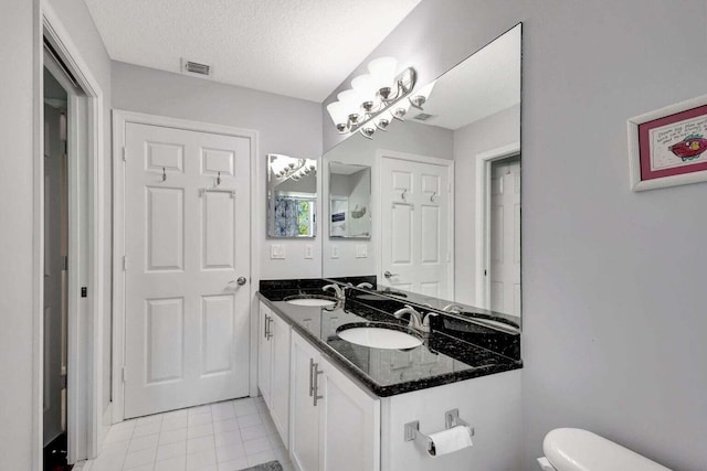 bathroom featuring vanity, tile patterned flooring, toilet, and a textured ceiling