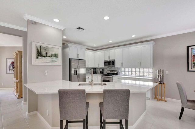 kitchen with white cabinets, sink, light tile patterned flooring, a breakfast bar area, and appliances with stainless steel finishes