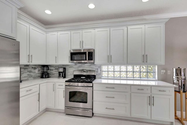 kitchen with crown molding, stainless steel appliances, backsplash, light tile patterned floors, and white cabinetry