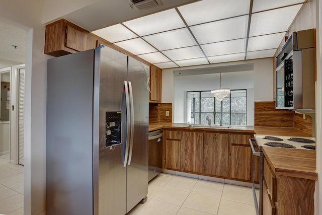 kitchen featuring an inviting chandelier, pendant lighting, sink, stainless steel appliances, and light tile patterned floors