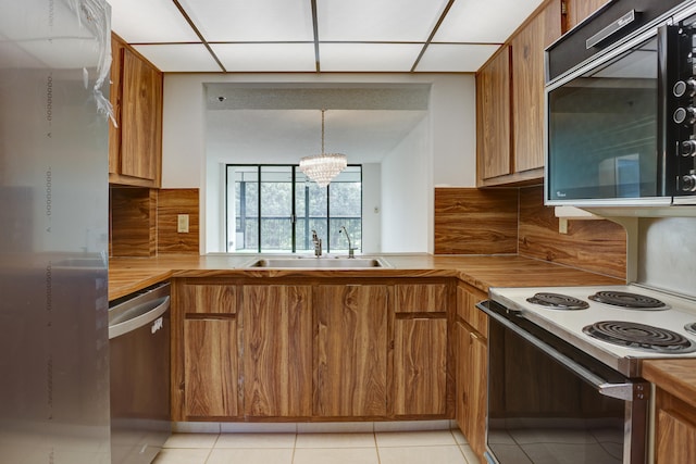 kitchen with tasteful backsplash, pendant lighting, a notable chandelier, sink, and stainless steel dishwasher