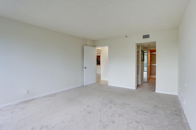 empty room featuring light carpet and a textured ceiling