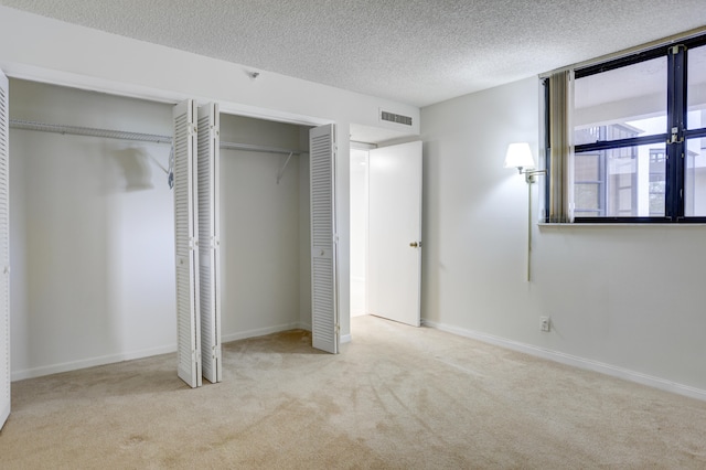 unfurnished bedroom featuring light colored carpet, multiple closets, and a textured ceiling