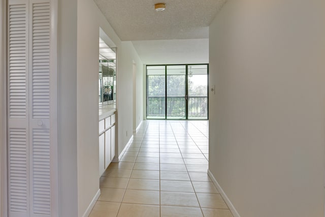 hall featuring expansive windows, light tile patterned floors, and a textured ceiling