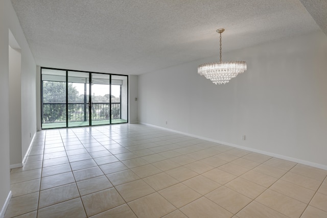 tiled empty room with expansive windows, a textured ceiling, and an inviting chandelier