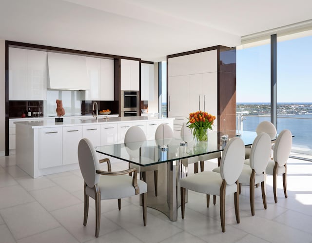 tiled dining area featuring sink, a water view, and a wall of windows