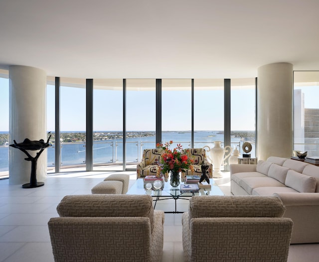 living room featuring floor to ceiling windows, a water view, a healthy amount of sunlight, and light tile patterned floors