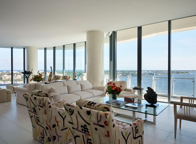 living room featuring light tile patterned floors, a water view, and a wall of windows