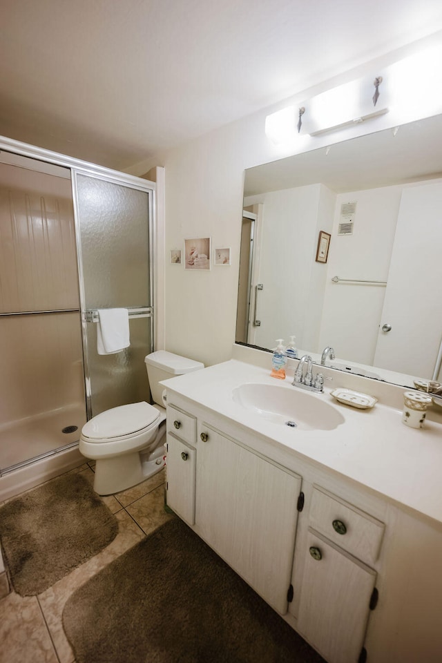 bathroom featuring vanity, toilet, a shower with door, and tile patterned floors