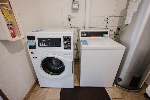 laundry area with light tile patterned flooring, washing machine and clothes dryer, and water heater