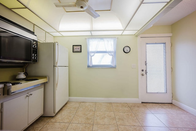 kitchen featuring ceiling fan, white refrigerator, light tile patterned floors, and white cabinets