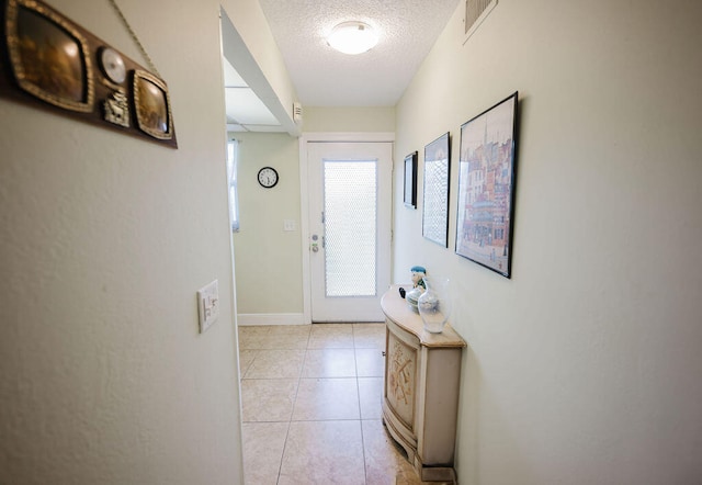 doorway with light tile patterned floors and a textured ceiling