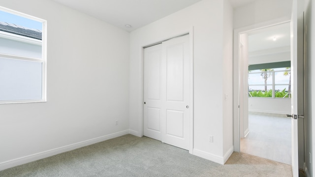 unfurnished bedroom with a closet, multiple windows, and light carpet