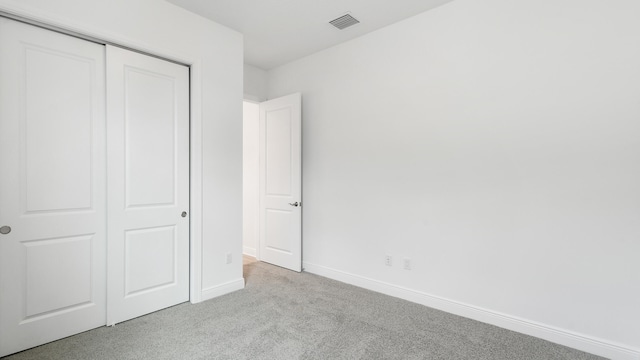 unfurnished bedroom with light colored carpet and a closet